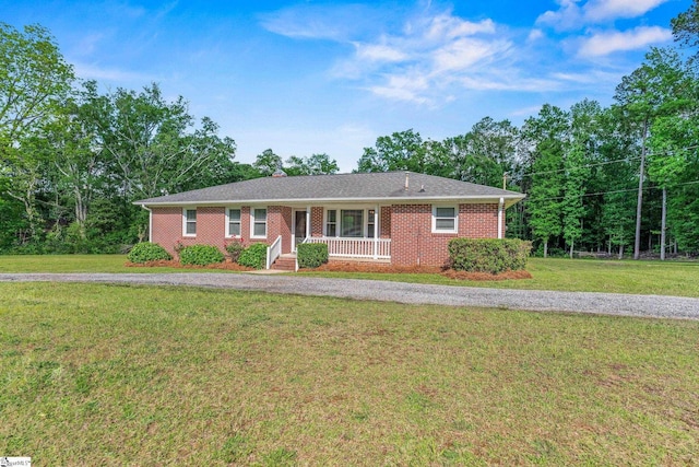 single story home featuring a porch, a front yard, driveway, and brick siding
