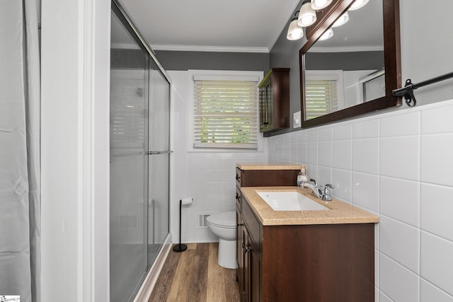 bathroom featuring tile walls, a stall shower, wood finished floors, crown molding, and vanity