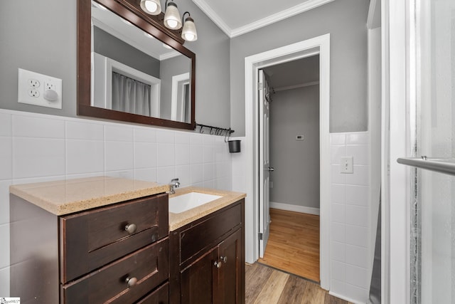 bathroom with tile walls, ornamental molding, vanity, wood finished floors, and wainscoting