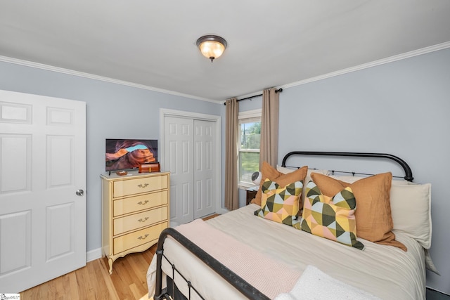 bedroom with light wood-type flooring, ornamental molding, a closet, and baseboards