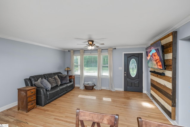 living room featuring a ceiling fan, ornamental molding, baseboards, and light wood-type flooring