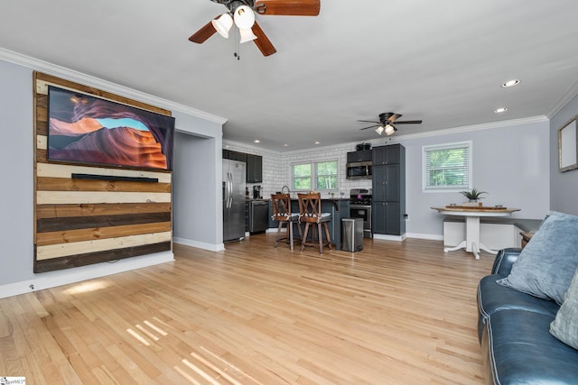 living room with a ceiling fan, crown molding, light wood-style flooring, recessed lighting, and baseboards