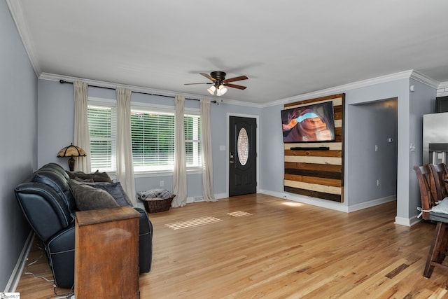 living area featuring ornamental molding, a ceiling fan, baseboards, and light wood finished floors