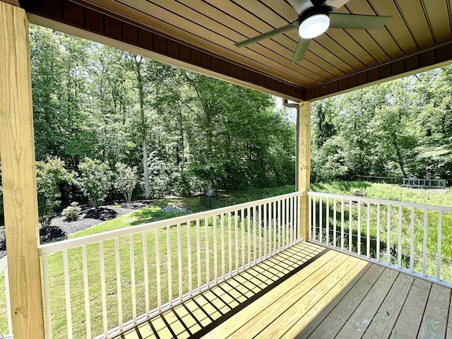 wooden terrace with ceiling fan, a lawn, and view of scattered trees