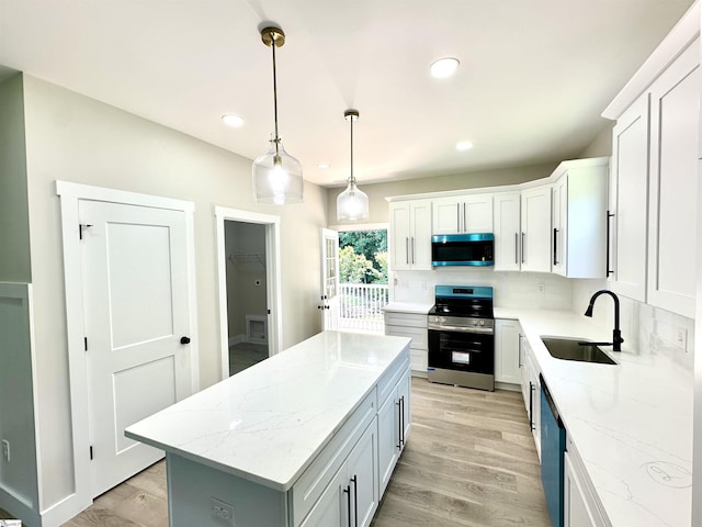 kitchen featuring appliances with stainless steel finishes, a sink, decorative backsplash, a kitchen island, and white cabinetry