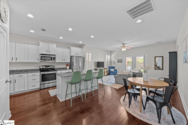 6 Kelvyn St, Greer, SC 29651 - kitchen with stainless steel appliances, an island with sink, white cabinets, ceiling fan, and a breakfast bar