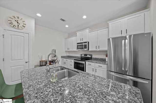 6 Kelvyn St, Greer, SC 29651 - kitchen featuring stainless steel appliances, a sink, white cabinets, an island with sink, and dark stone counters