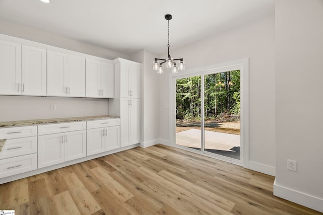 kitchen with a chandelier, baseboards, light wood-style floors, white cabinetry, and decorative light fixtures