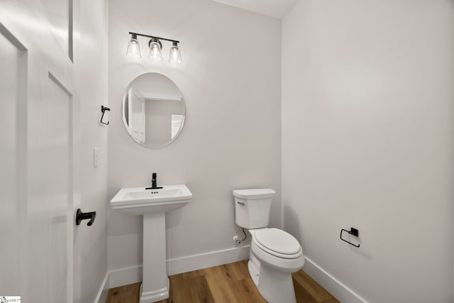 bathroom with wood finished floors, toilet, baseboards, and a sink