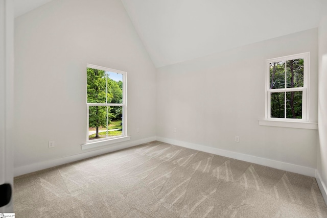 carpeted spare room featuring plenty of natural light, lofted ceiling, and baseboards