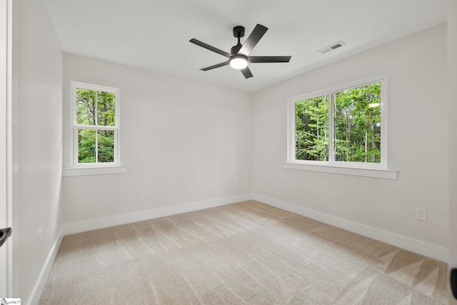 carpeted spare room featuring baseboards and a ceiling fan