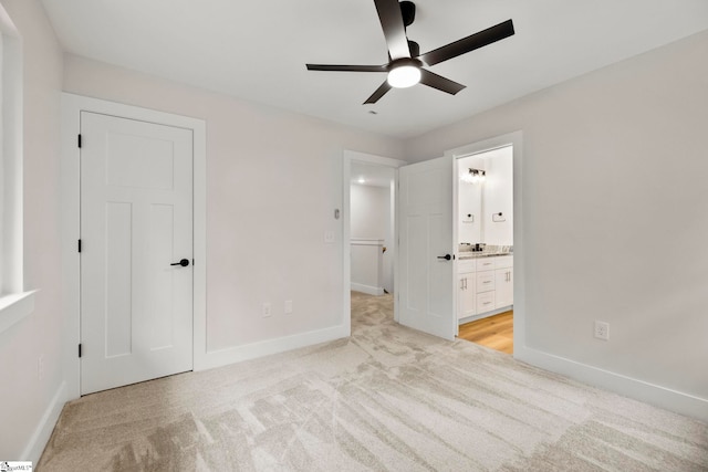 unfurnished bedroom featuring light colored carpet, baseboards, connected bathroom, and ceiling fan