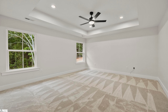 empty room featuring baseboards, a tray ceiling, healthy amount of natural light, light colored carpet, and recessed lighting