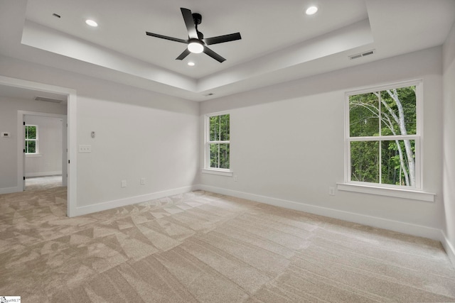 unfurnished room with a tray ceiling, light carpet, baseboards, a ceiling fan, and recessed lighting