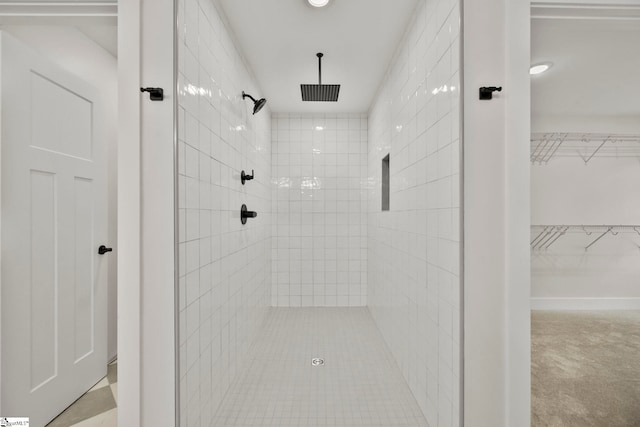 full bath featuring tiled shower and a walk in closet