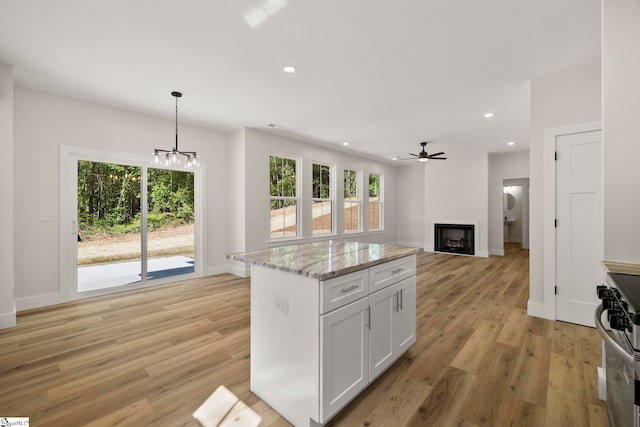 kitchen featuring stainless steel range with gas stovetop, light wood-style flooring, a chandelier, recessed lighting, and baseboards