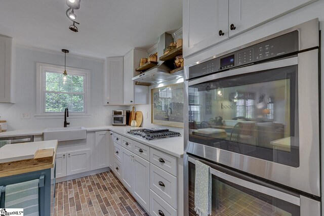 202 Roberta Dr, Greenville, SC 29615 - kitchen featuring appliances with stainless steel finishes, a sink, white cabinetry, brick patterned flooring, and pendant lighting