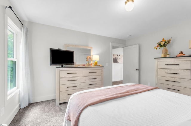 bedroom with light colored carpet and baseboards