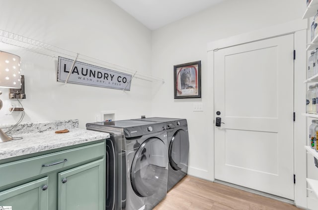 laundry room with light wood-style flooring, independent washer and dryer, and cabinet space