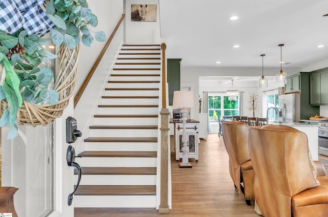 stairs featuring wood finished floors and recessed lighting