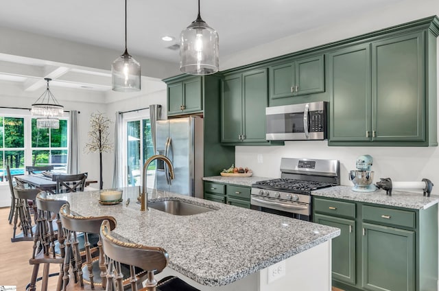 kitchen with stainless steel appliances, green cabinets, a sink, light stone countertops, and beam ceiling