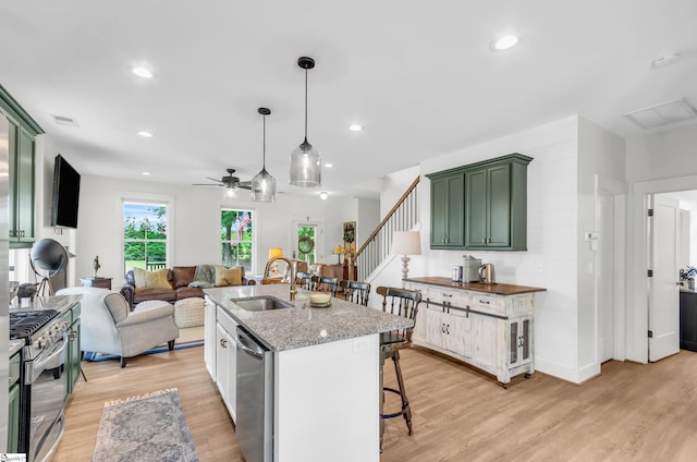 kitchen featuring green cabinetry, a sink, appliances with stainless steel finishes, ceiling fan, and light wood-style floors