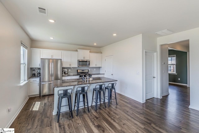 115 Slateford Cir, Piedmont, SC 29673 - kitchen with stainless steel appliances, a breakfast bar, a kitchen island with sink, dark wood-style floors, and white cabinetry