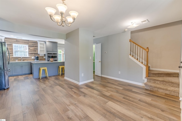 105 Bitternut Ln, Taylors, SC 29687 - unfurnished living room featuring a sink, light wood-style floors, stairs, a chandelier, and baseboards
