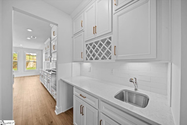 kitchen with a sink, white cabinets, tasteful backsplash, and recessed lighting