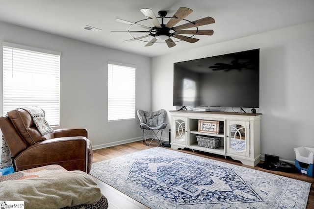 living room with ceiling fan, baseboards, and wood finished floors