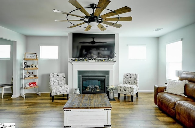 living area featuring a glass covered fireplace, plenty of natural light, baseboards, and dark wood-type flooring