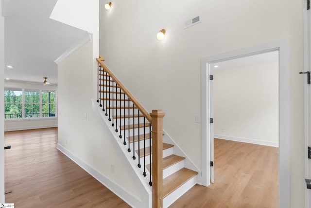 stairway featuring wood finished floors, baseboards, and recessed lighting