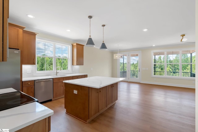 kitchen with appliances with stainless steel finishes, a sink, a center island, light wood-style floors, and healthy amount of natural light