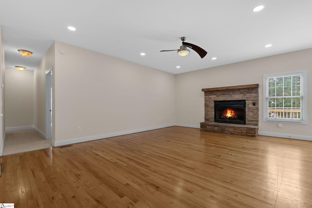 unfurnished living room with light wood finished floors, a ceiling fan, recessed lighting, a fireplace, and baseboards