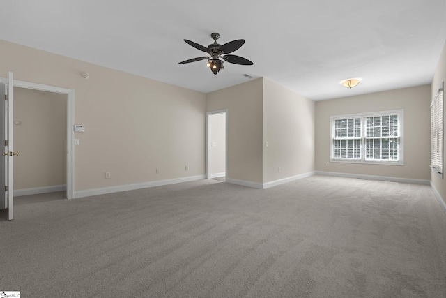spare room featuring light colored carpet, baseboards, and ceiling fan