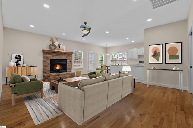 living room featuring light wood-style flooring, baseboards, a fireplace, and recessed lighting
