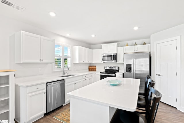 5 Timberwild Dr, Greenville, SC 29605 - kitchen featuring appliances with stainless steel finishes, a center island, a breakfast bar area, wood finished floors, and white cabinetry