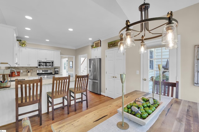 dining area with light wood-type flooring, ornamental molding, and recessed lighting