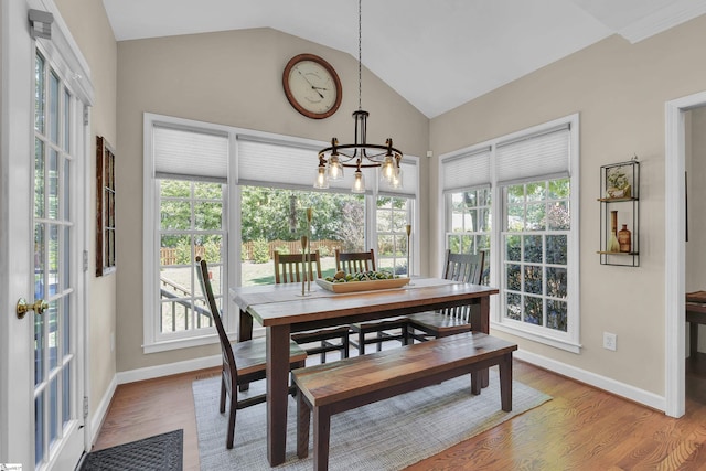dining room with vaulted ceiling, plenty of natural light, a chandelier, and wood finished floors