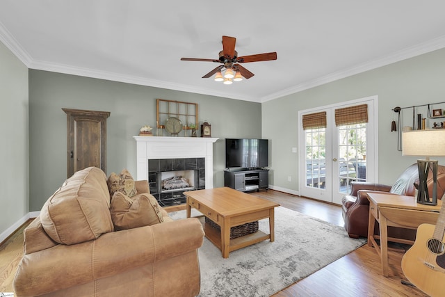 living area featuring ornamental molding, ceiling fan, wood finished floors, baseboards, and a fireplace