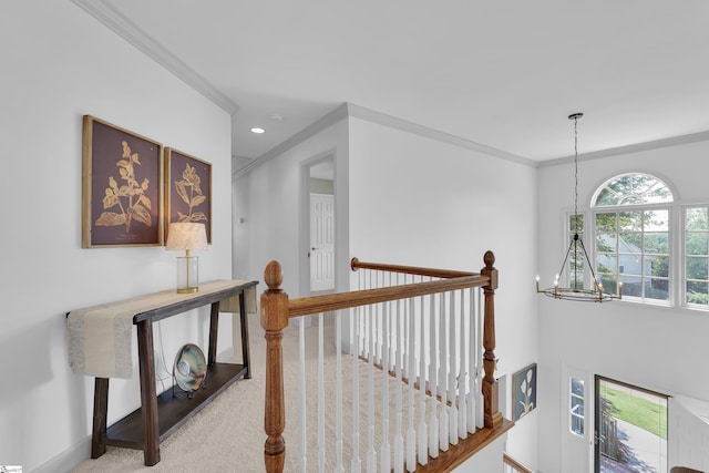 hallway with a chandelier, an upstairs landing, ornamental molding, carpet flooring, and baseboards