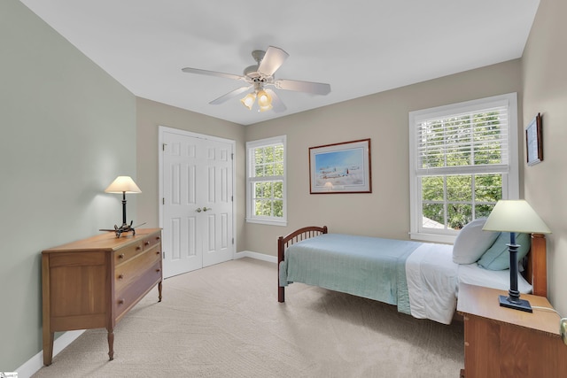 bedroom featuring light colored carpet, baseboards, multiple windows, and a closet