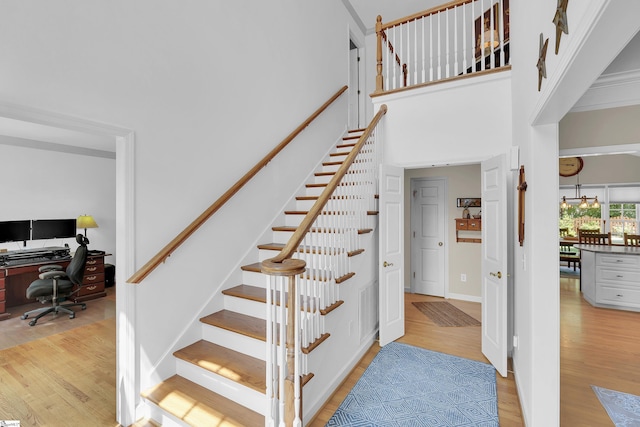 stairway featuring wood finished floors, a chandelier, and a high ceiling
