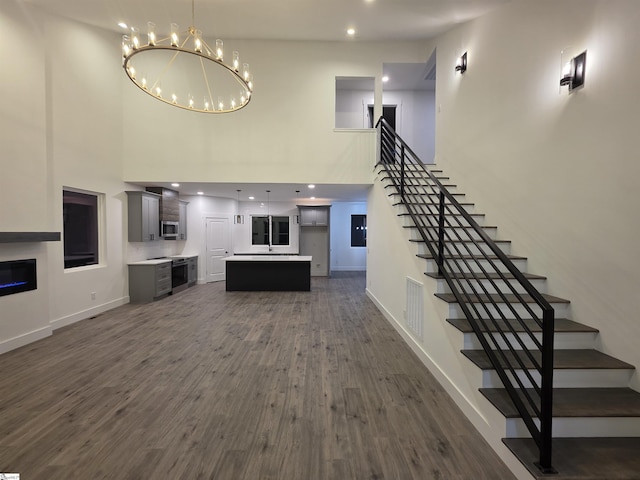 402 Edgewater Dr, Anderson, SC 29626 - unfurnished living room with a high ceiling, dark wood-type flooring, stairs, a chandelier, and baseboards