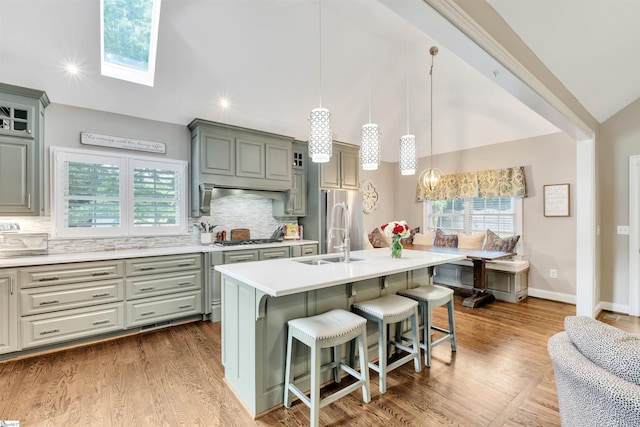 kitchen featuring appliances with stainless steel finishes, light countertops, a breakfast bar area, backsplash, and vaulted ceiling