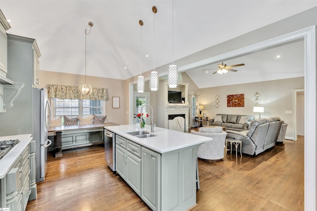 kitchen with a sink, vaulted ceiling, a fireplace, light countertops, and a ceiling fan