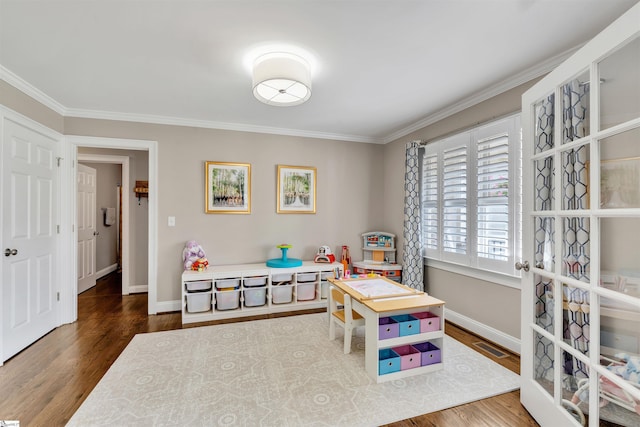 game room with wood finished floors, baseboards, and crown molding