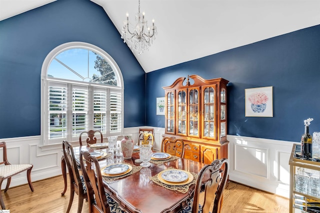 dining room featuring a chandelier, a wainscoted wall, wood finished floors, high vaulted ceiling, and a decorative wall