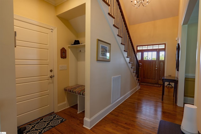 foyer with wood finished floors, stairway, baseboards, and a chandelier