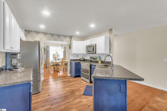239 Walcott Dr, Lyman, SC 29365 - kitchen with appliances with stainless steel finishes, a sink, blue cabinets, a peninsula, and light wood finished floors